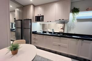 a kitchen with white cabinets and a white table at Santorini Urban Studio • conforto e estilo in Londrina