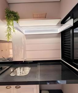 a kitchen with a sink and a microwave at Santorini Urban Studio • conforto e estilo in Londrina