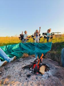a group of people sitting around a camp fire at Lagom - Logeren in 't groen in Nieuwerkerken