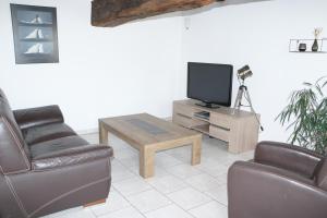 a living room with a couch and a table and a tv at Gîte de l'Aubinière in Brissac-Quincé