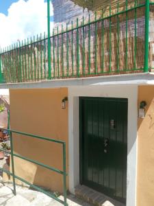a green door on a building with a balcony at The stone house in Doukádes +3 photos