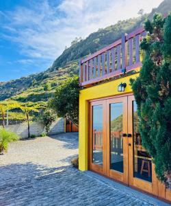 a yellow building with glass doors and a mountain at Ribeira da Janela Paradise View in Porto Moniz +16 photos