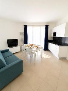 a living room with a table and a blue couch at Villa Marina Apartments - Agenzia Cocal in Caorle