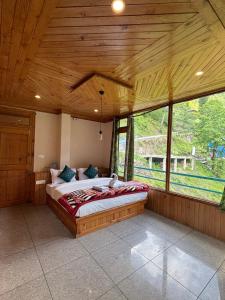 a bedroom with a large bed in a room with windows at Venky's Shoja in Jibhi