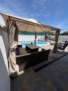 a patio with a umbrella and a table and a pool at Niza Beach Sunset Stay in Málaga