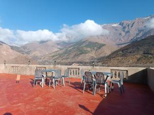 a group of tables and chairs on a balcony with mountains at Toubkal Guesthouse in Imlil