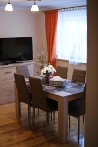 een eettafel met stoelen en een televisie bij Apartament Ametyst in Jelenia Góra