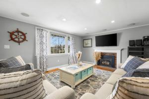 a living room with two couches and a fireplace at Dog-Friendly Cape Cod Getaway with Fire Pit Yard in South Yarmouth +14 photos