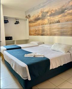 two beds in a room with a painting on the wall at Coqueiros Express Hotel in Maceió +25 photos