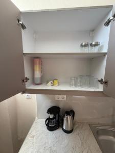 a kitchen with a cupboard with a tea kettle and a sink at Derveni Nest Apartment in Rodhéa
