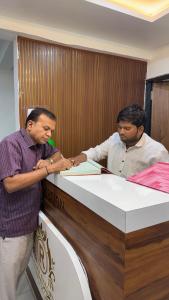 two men are standing at a desk at THE RAMA Executive in Tuljapur