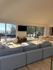 a living room with a large couch and a table at Chalet L'Estuaire, River View, Spa in Saint-Joseph-de-la-Rive