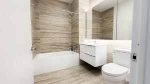 a bathroom with a toilet and a tub and a sink at Stylish 3BR Luxury Retreat in the Heart of FiDi in New York