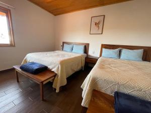 a bedroom with two beds and a table and a window at Tapalpa Hotel Casa Colibrí in Tapalpa