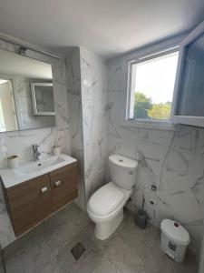 a white bathroom with a toilet and a sink at Alexandras Studio in Corfu
