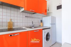 a kitchen with orange cabinets and a washing machine at Lido degli Estensi Fronte Mare e Balcone in Comacchio +18 photos
