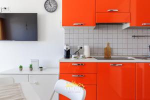 a kitchen with orange cabinets and a clock on the wall at Lido degli Estensi Fronte Mare e Balcone in Comacchio