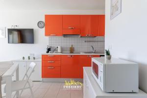 a kitchen with orange cabinets and a white refrigerator at Lido degli Estensi Fronte Mare e Balcone in Comacchio