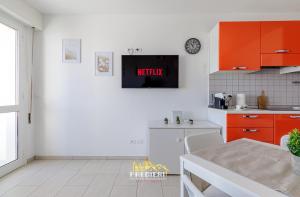 a kitchen with orange cabinets and a tv on the wall at Lido degli Estensi Fronte Mare e Balcone in Comacchio