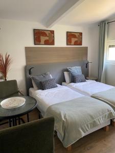 two beds in a room with a table and a chair at Résidence Cosyade équipée d'un parking privé gratuit in Bourbourg