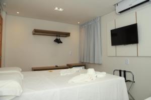 ein Schlafzimmer mit einem weißen Bett und einem Flachbildfernseher in der Unterkunft Mairí Hotel in Itaituba