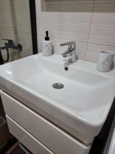 a white bathroom sink with two cups on it at Luxury Park Apartment Strumica in Strumica +21 photos