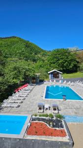 a swimming pool with lounge chairs and a hill at M&M Bazen resort Goražde in Goražde