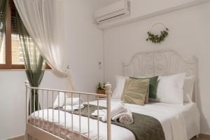 a white bedroom with a bed with white and green pillows at Miranda's Apartments in Koskinou