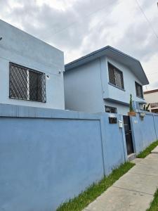 a white house with a blue wall and a fence at Cumbre Guesthouse in Monterrey