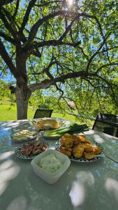 a table with plates of food on it with a tree at M&M Bazen resort Goražde in Goražde