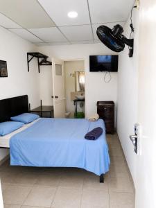 a bedroom with a bed with a blue blanket and a television at Orison Managua in Managua +6 photos