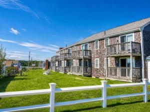 a brick building with balconies and a white fence at Colonial Acres Resort in Yarmouth