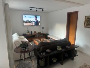 a living room with a couch and a tv on the wall at veleiros g3 in Ibiúna