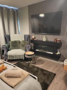 a living room with a large television and a couch at Holmleigh Place in Buxton