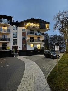 a building with a car parked in a parking lot at Apartamenty Riverside Lębork in Lębork
