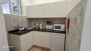 a small kitchen with white cabinets and a microwave at Vila Calaça in Funchal