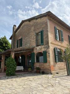 an old brick house with green shutters on it at Azalea Guest House in Siena