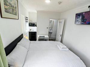 a bedroom with a white bed and a kitchen at Cherry Studio - Self Contained One-Bed Studio Flat in Oxford