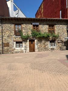a stone building with a door on a brick street at Hospedería La Bogadera in La Robla