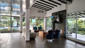 a living room with a couch and chairs and windows at Finca Santa Rita in Pereira
