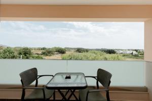 a table and chairs on a balcony with a large window at Valentina's Luxe Apartment in Mastihari