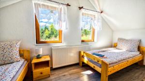 a bedroom with two beds and two windows at Tea Vendégházak in Ghiduţ