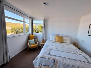a bedroom with a bed and a large window at Windy Garden in Marahau