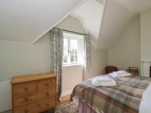 a bedroom with a bed with a dresser and a window at Middle Cottage in Salisbury