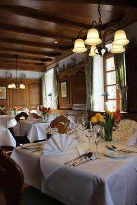a dining room with tables with white tablecloths and flowers at Hotel Kallstadter Hof in Kallstadt