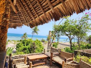 a patio with a table and chairs and the beach at Mango Lodge MSAMBWENI in Kisimachande