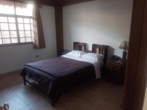 a bedroom with a bed with a blue blanket and a window at hotel turistico in Huaraz
