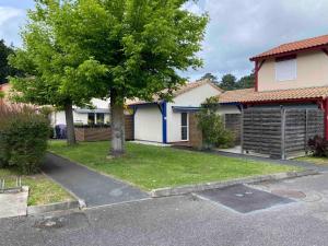 a house with a tree in front of a driveway at MAISON les ARCADES in Soustons