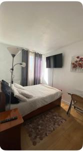 a bedroom with a bed and a lamp and a table at chambre Cosy et Chambre Sam in Rosny-sous-Bois