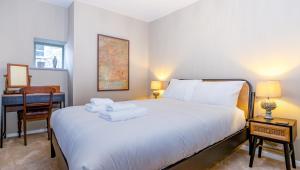 a bedroom with a white bed with a desk and a chair at Cottage on Wells High Street in Wells